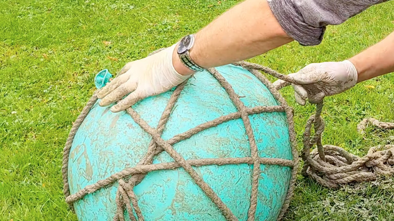 woman creating DIY garden decor by wrapping rope around an inflated balloon