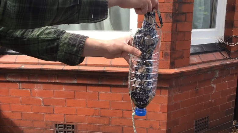 Male hands placing a wet umbrella inside a plastic bottle holder