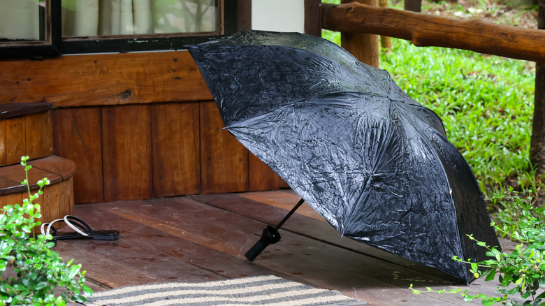 A wet black umbrella drying on a home's porch