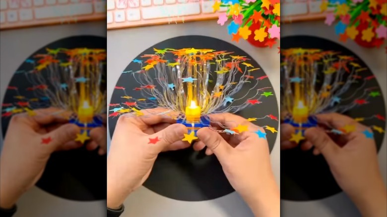 Two hands hold a star light made from a plastic bottle.