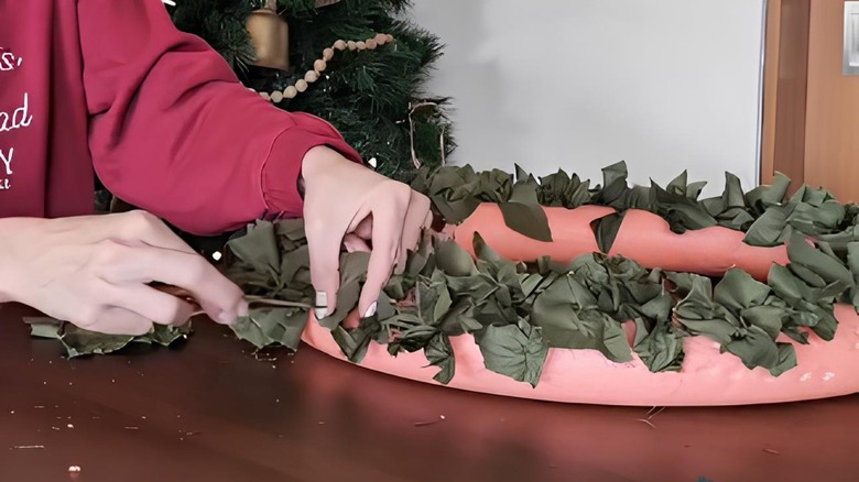 Handcrafting a wreath out of scrap fabric and a pink pool noodle.