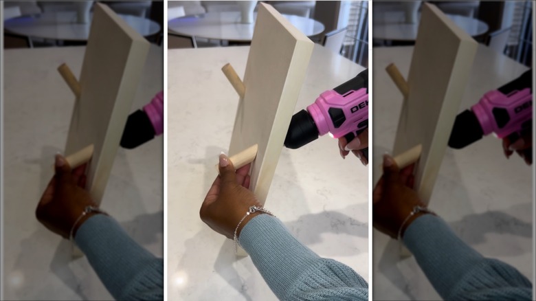 person using a drill to screw dowels onto a wooden base base