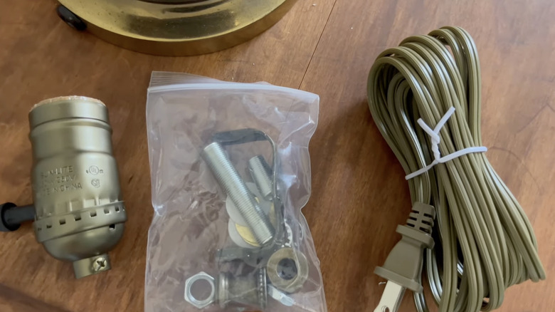 A brass lamp kit on a wooden tabletop.