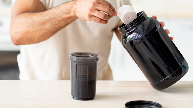 A man scoops protein powder into a shaker.