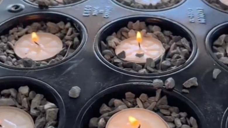 close up of muffin tin filled with pebbles and tea lights
