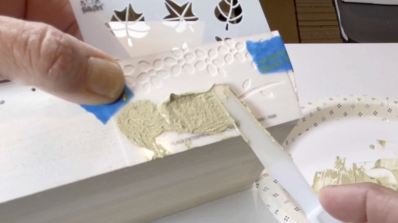 Hands painting a stencil onto a wooden box