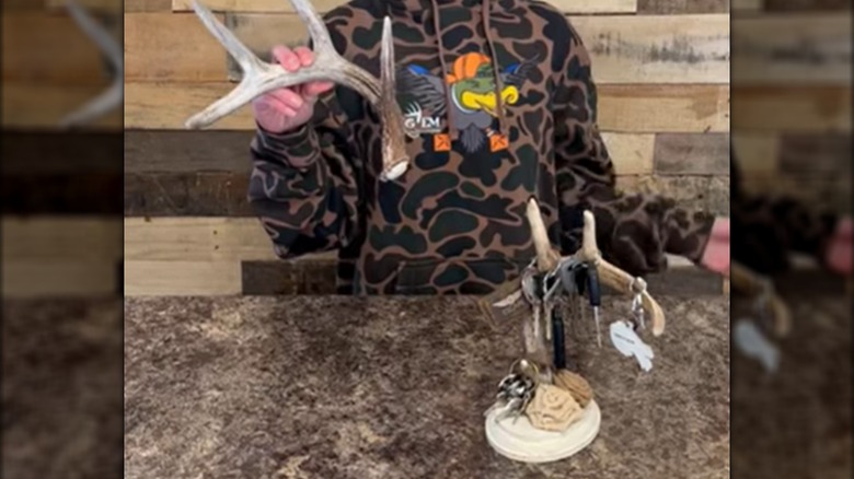 A person showing off an antler drop and a handmade antler hanging rack.