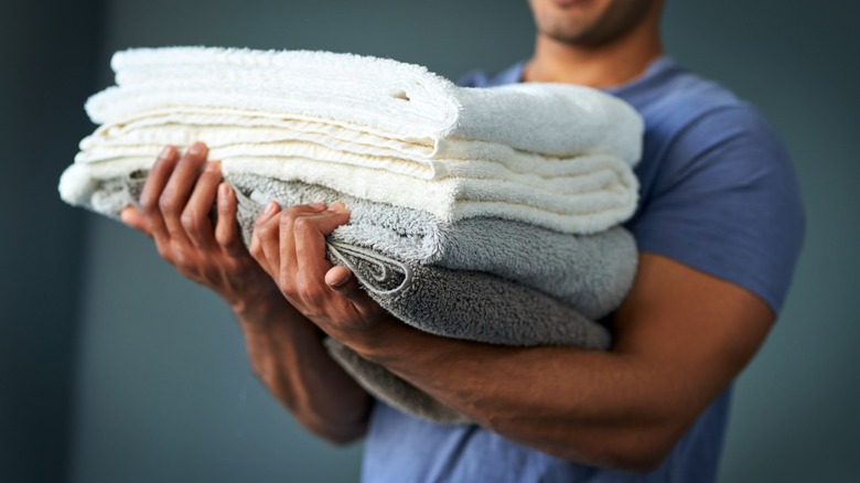 Man holding stack of folded bath towels