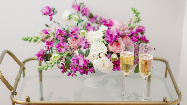 Bar cart on wheels with flowers and champagne