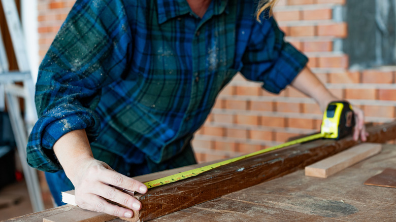 A woman measures a piece of wood