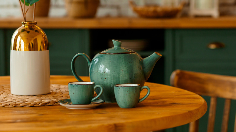 Green teapot and teacups on a table