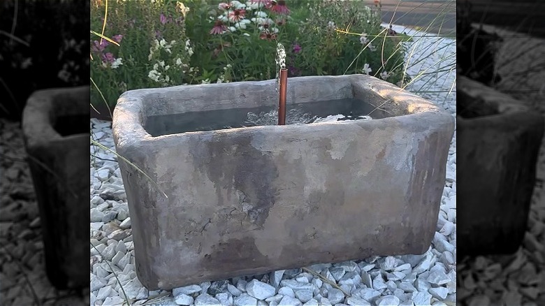 A DIY water feature made from a repurposed styrofoam cooler, concrete, and stones.