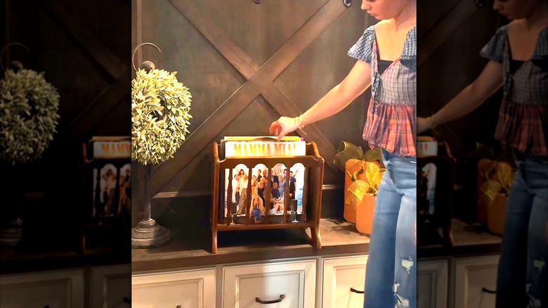 Woman placing records in wooden magazine rack