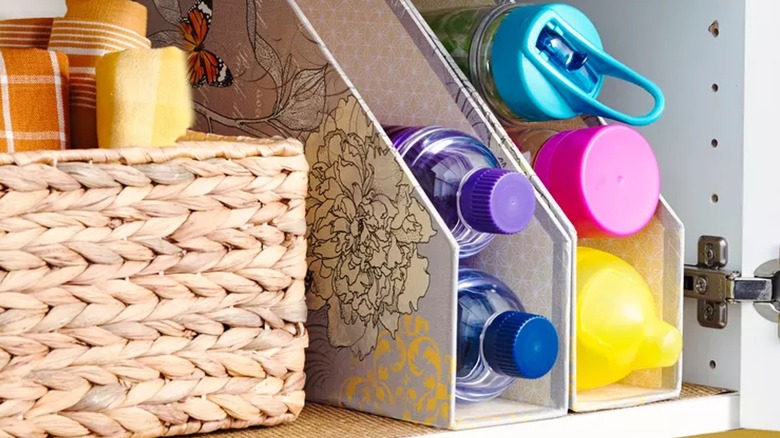 Magazine racks holding water bottles in cabinet