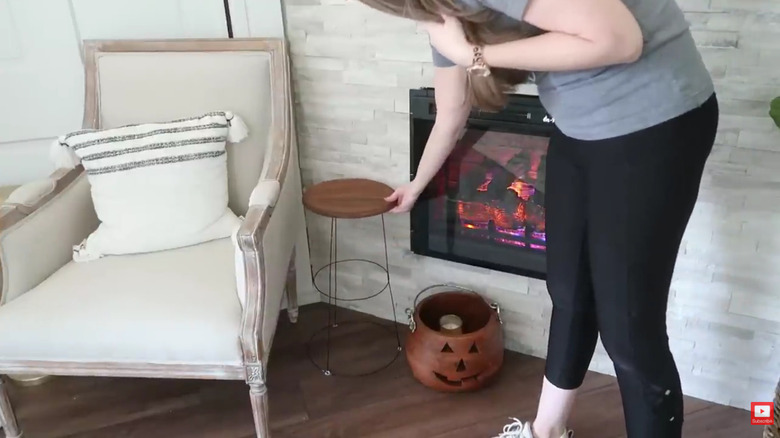 A woman setting a tomato trellis table beside an armchair