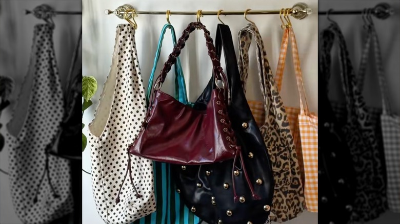 Purses hanging off of a towel rack