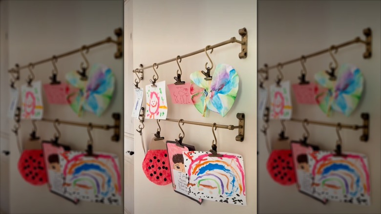 Kids' artwork hanging from towel bars on a wall