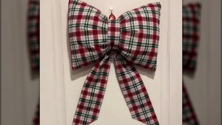 A checkered plush bow in red, green, and white hanging on door