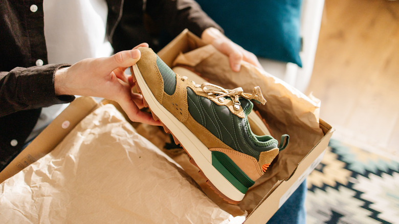 Person holding brand new shoe from shoebox