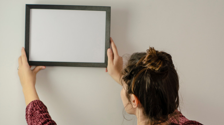 Woman hanging up frame