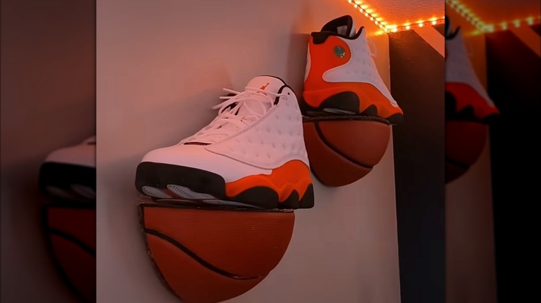 Red and white Jordan shoes resting on floating basketball shelves under yellow LED lights