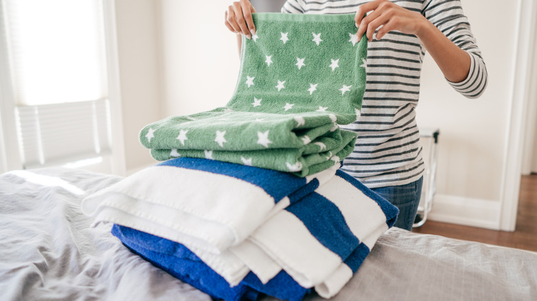 A person sorting through a collection of bath towels.