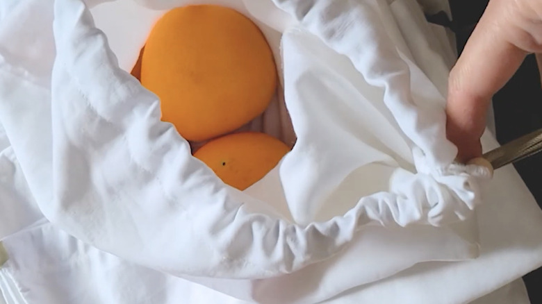 Produce bag made from an old bed sheet with draw string and oranges inside.