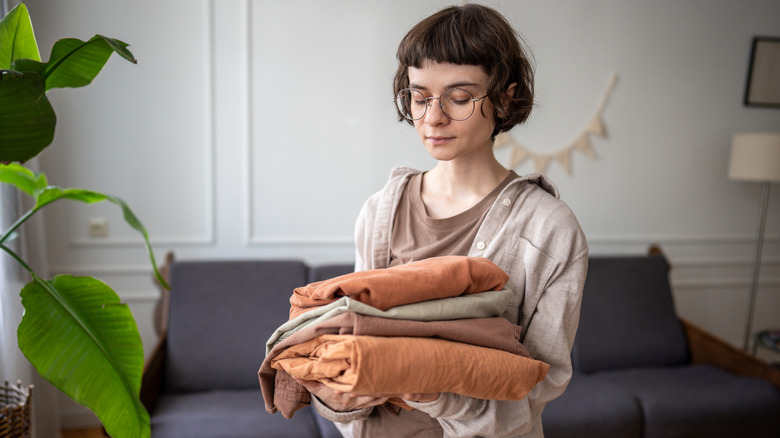 A woman looking at a stack of earth-toned sheets