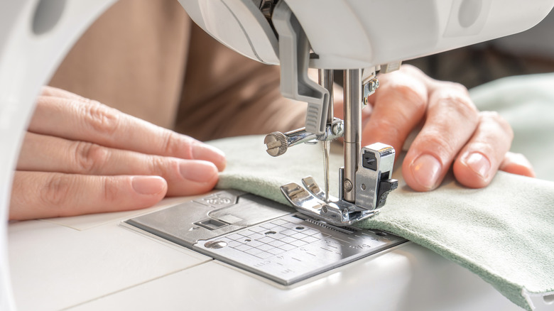 A person finishing the edges of a piece of fabric on a sewing machine