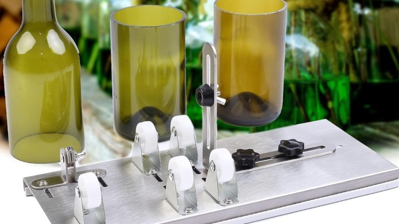 A glass bottle cutting device with cut bottles in the background.
