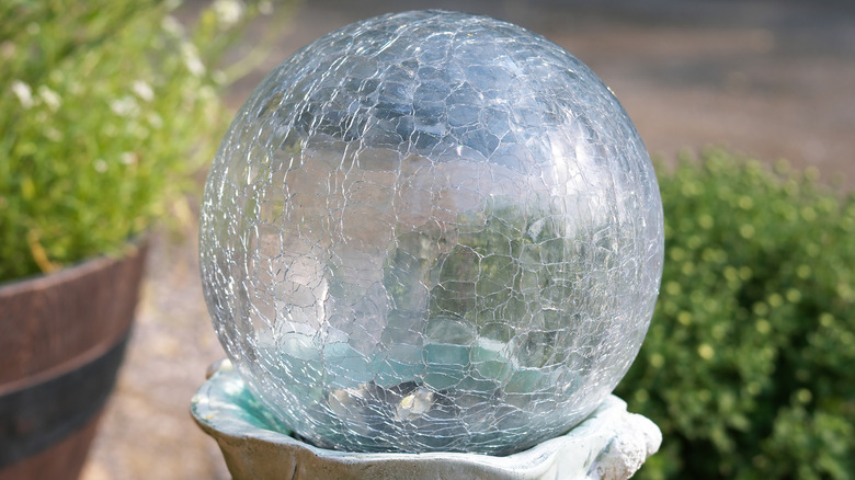 Clear, crackled glass ball on top of concrete pedestal.
