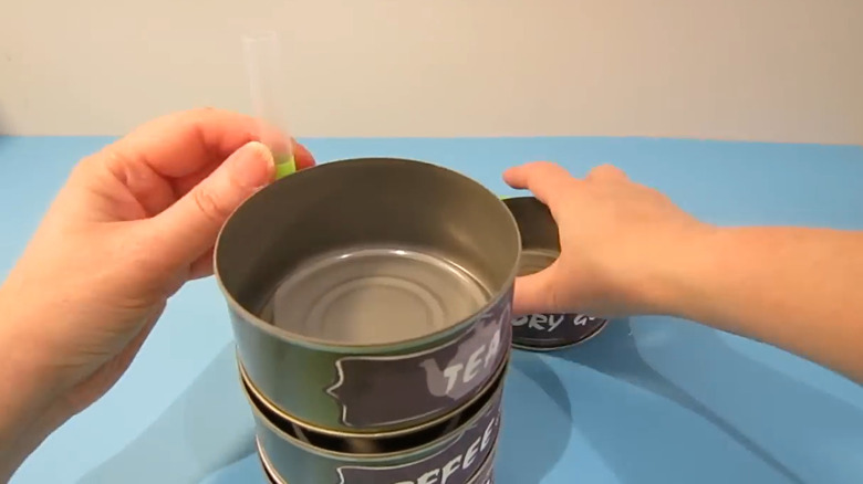 Person stacking tuna cans to make DIY jewelry holder