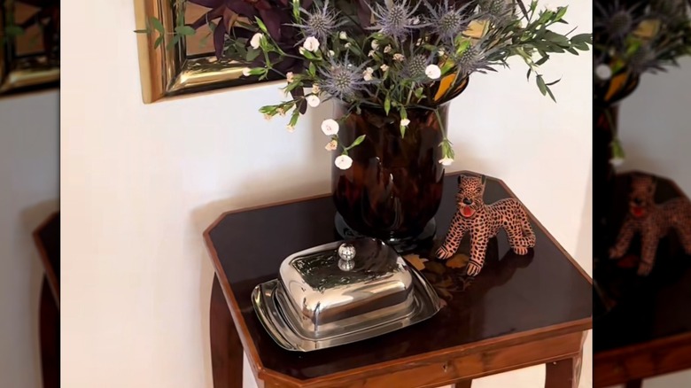 an entryway table features a vase, a leopard figurine, and an old butterdish for holding keys