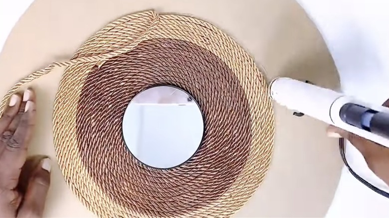 Woman assembling a DIY rope mirror on cardboard