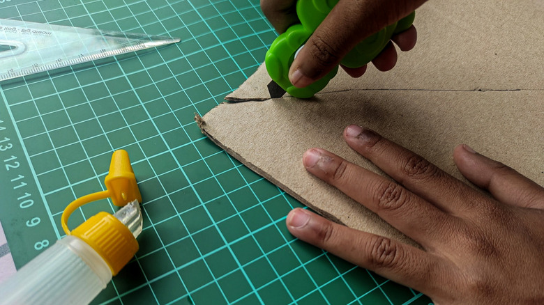 A person using a craft knife to cut carboard