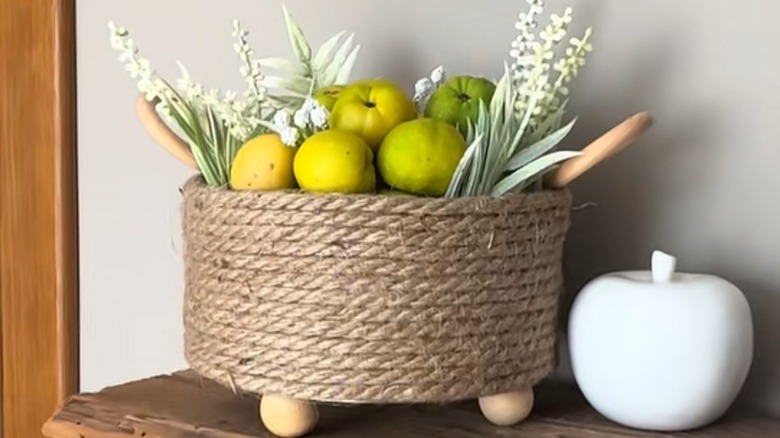 A jute-wrapped basket made from a cookie tin holds pears and faux flowers.