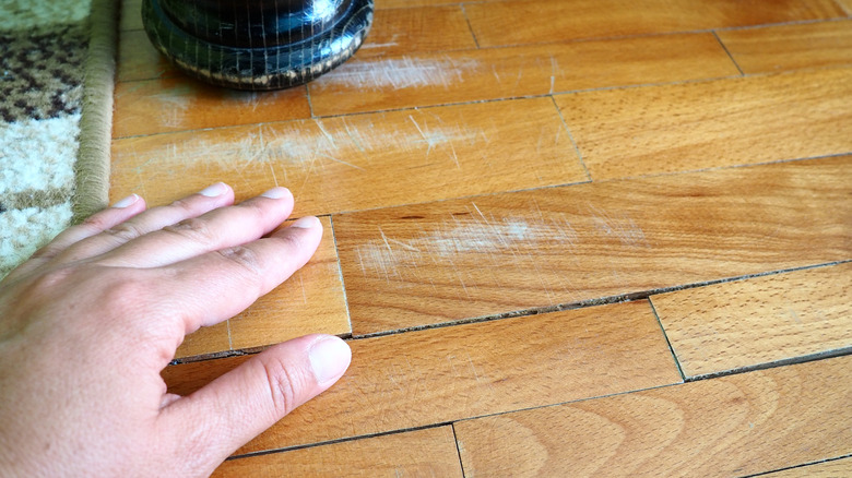 A hand cleaning a scratched floor