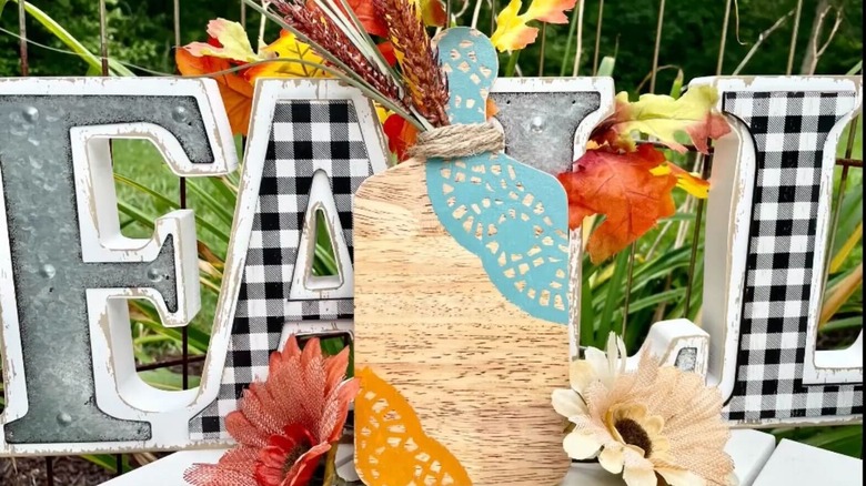 A decorative cutting board for kitchen décor made from painted Dollar Tree paper doilies and floral stems.