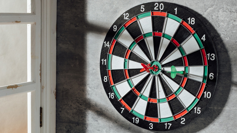 Dart board mounted on a gray wall near window