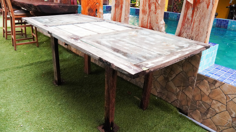 A rustic table made from an old door next to a pool