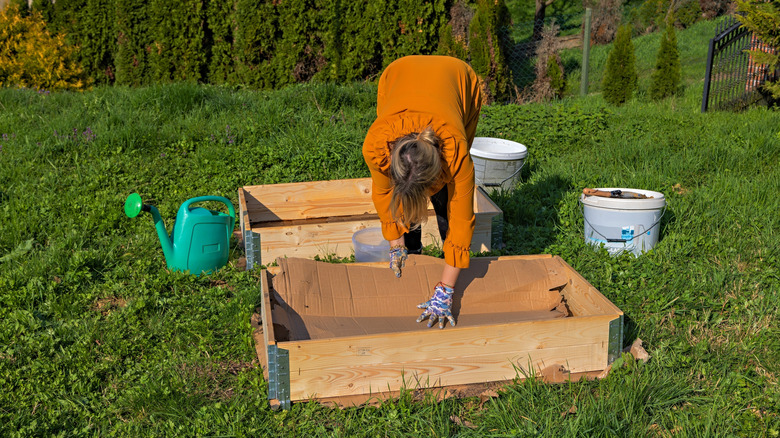 A person builds a DIY garden bed from scrap wood in their backyard.