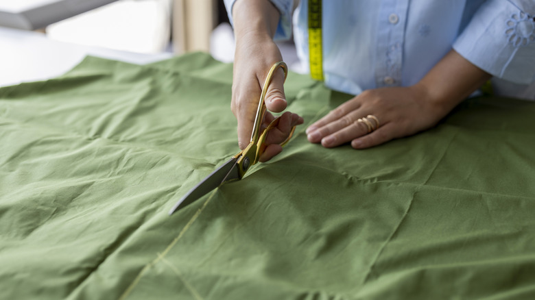 Someone cutting green fabric