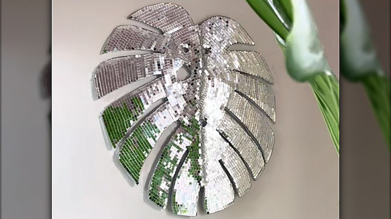 Shimmery wall decor made from the outline of a monstera leaf and covered with mirror tiles