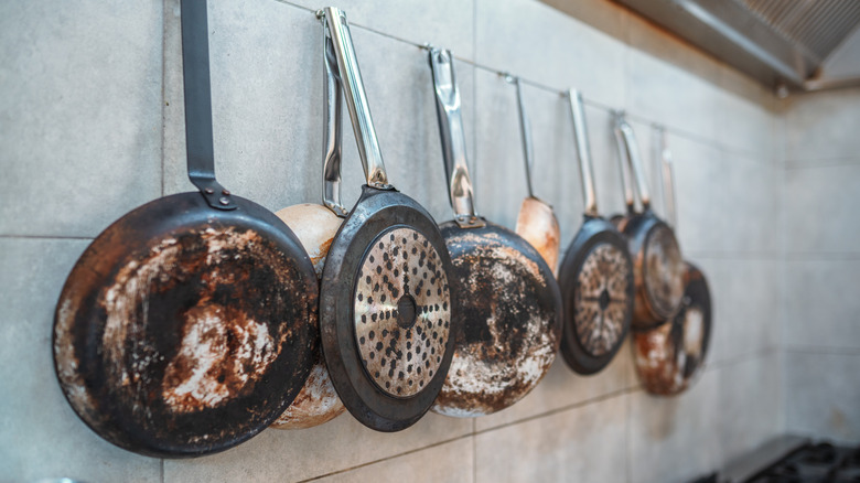 Old frying pans hanging on pot rack in kitchen