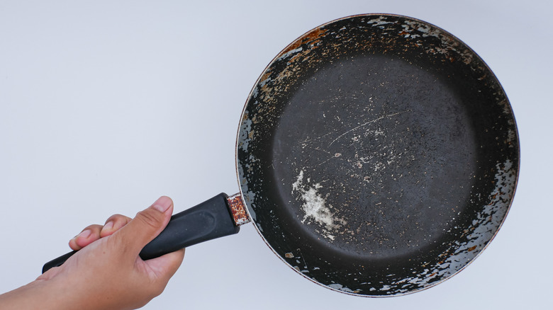 person holding old frying pan