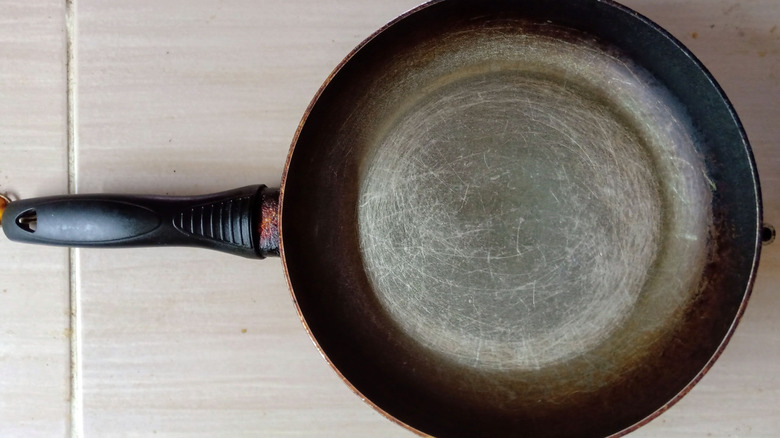 A scratched Teflon frying pan on a tile counter