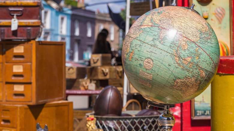An old globe in a store alongside other vintage and antique items.