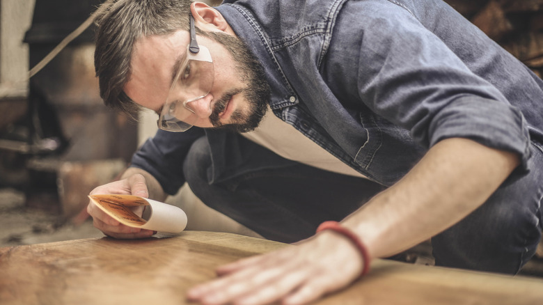 man sanding and smoothing wood for DIY