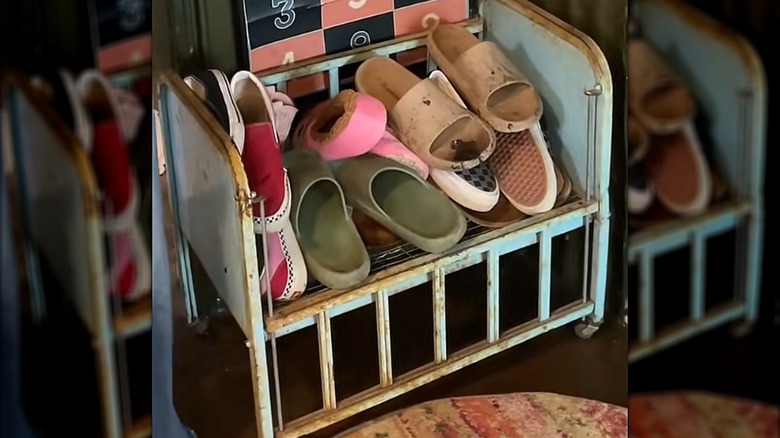Shoes in middle section of blue vintage doll bed frame.