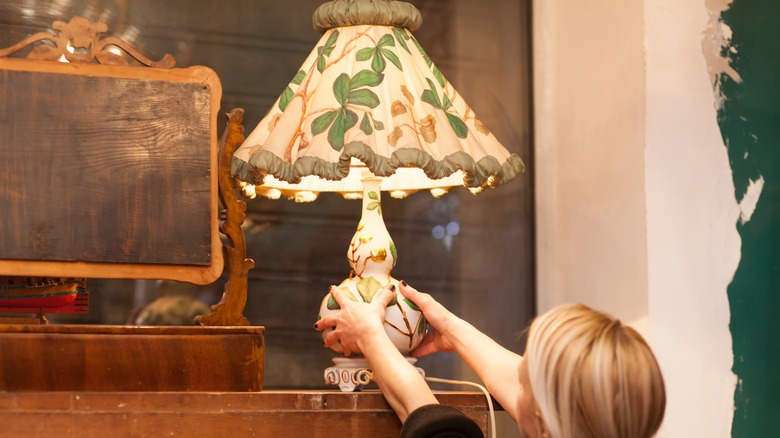 Woman pulling a vintage lamp from a store shelf